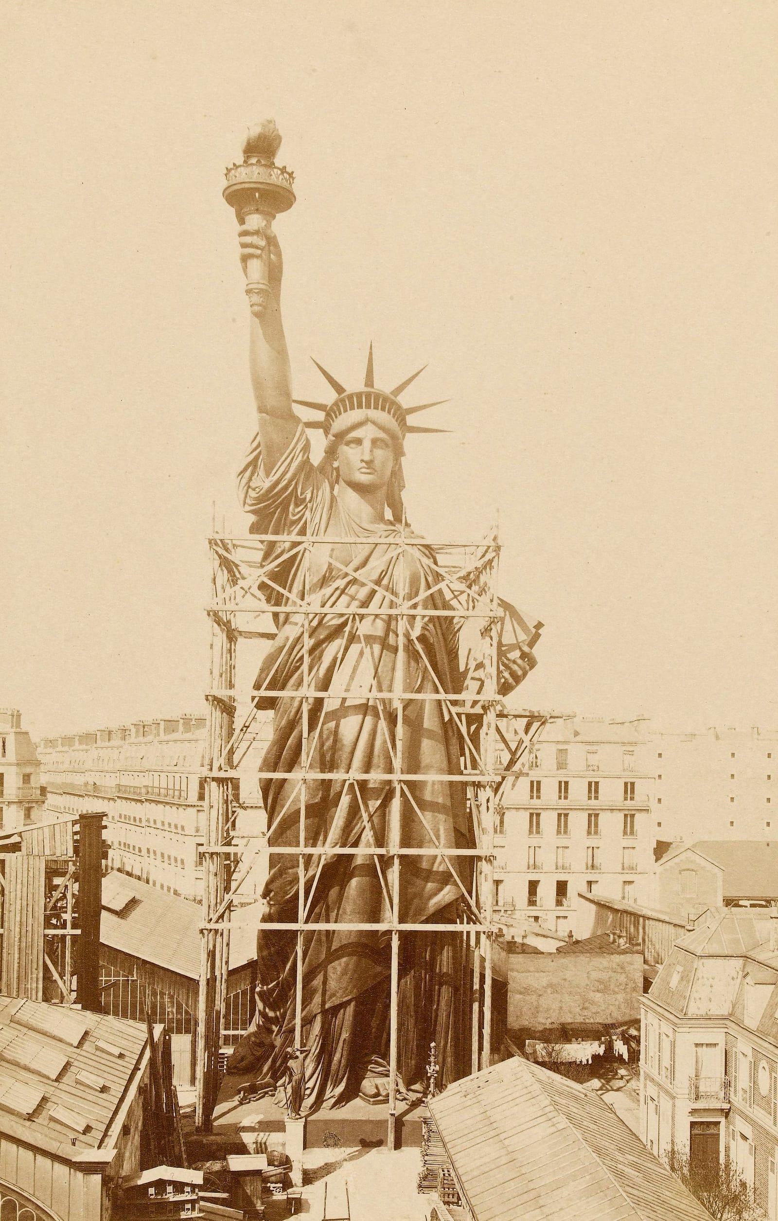 The Statue of Liberty, finished, standing in scaffolding above the rooftops of Paris in 1884
