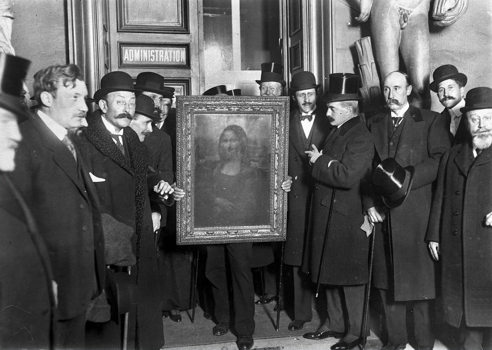 Men in overcoats and top hats crowd round the framed Mona Lisa, held up at a Louvre doorway marked Administration